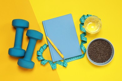 Weight loss concept. Flat lay composition with notebook, measuring tape and glass of water on color background