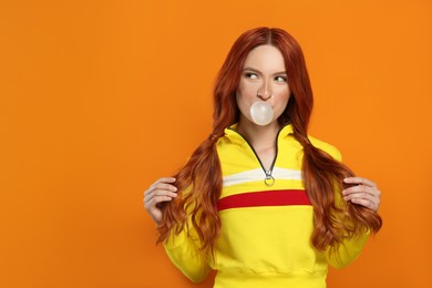 Photo of Portraitbeautiful woman blowing bubble gum on orange background. Space for text