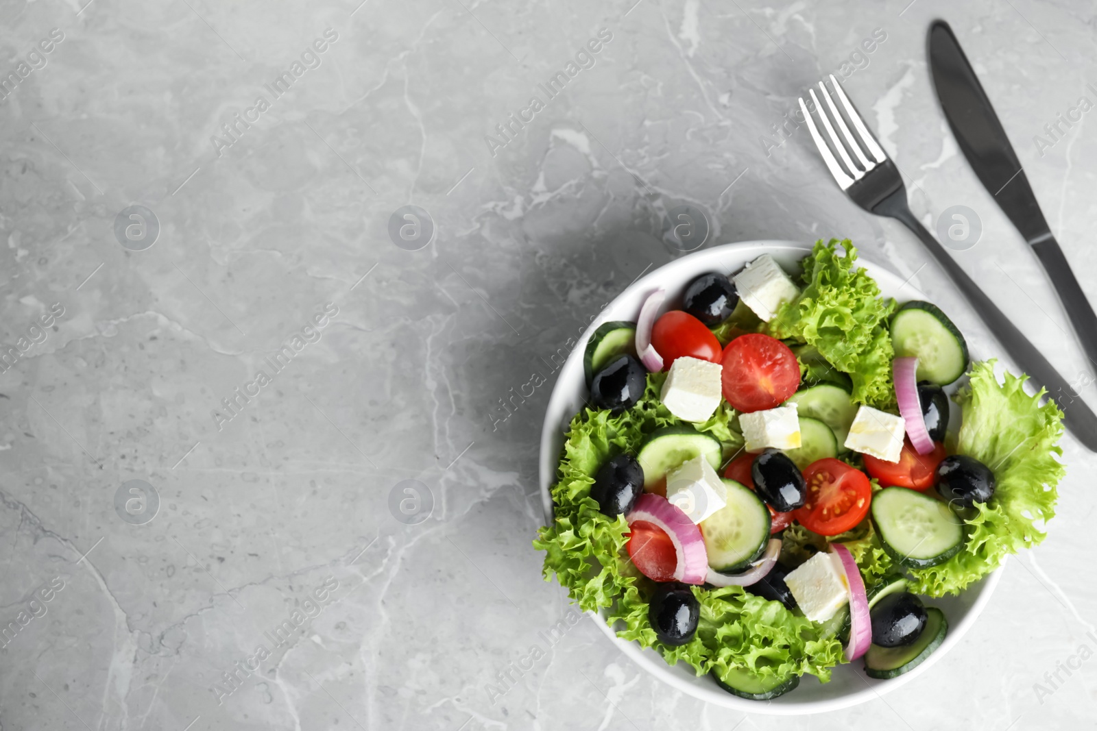 Photo of Tasty fresh Greek salad on grey marble table, flat lay. Space for text