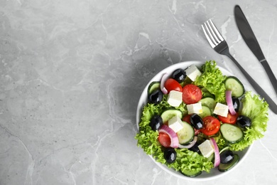 Photo of Tasty fresh Greek salad on grey marble table, flat lay. Space for text