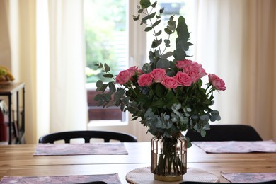 Beautiful bouquet of roses and napkins on wooden table indoors