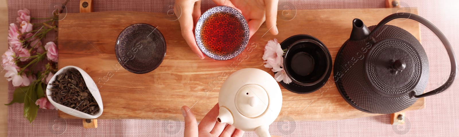 Image of Master and guest with freshly brewed tea during traditional ceremony at wooden table, top view. Banner design