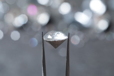 Photo of Tweezers with beautiful gemstone on blurred background