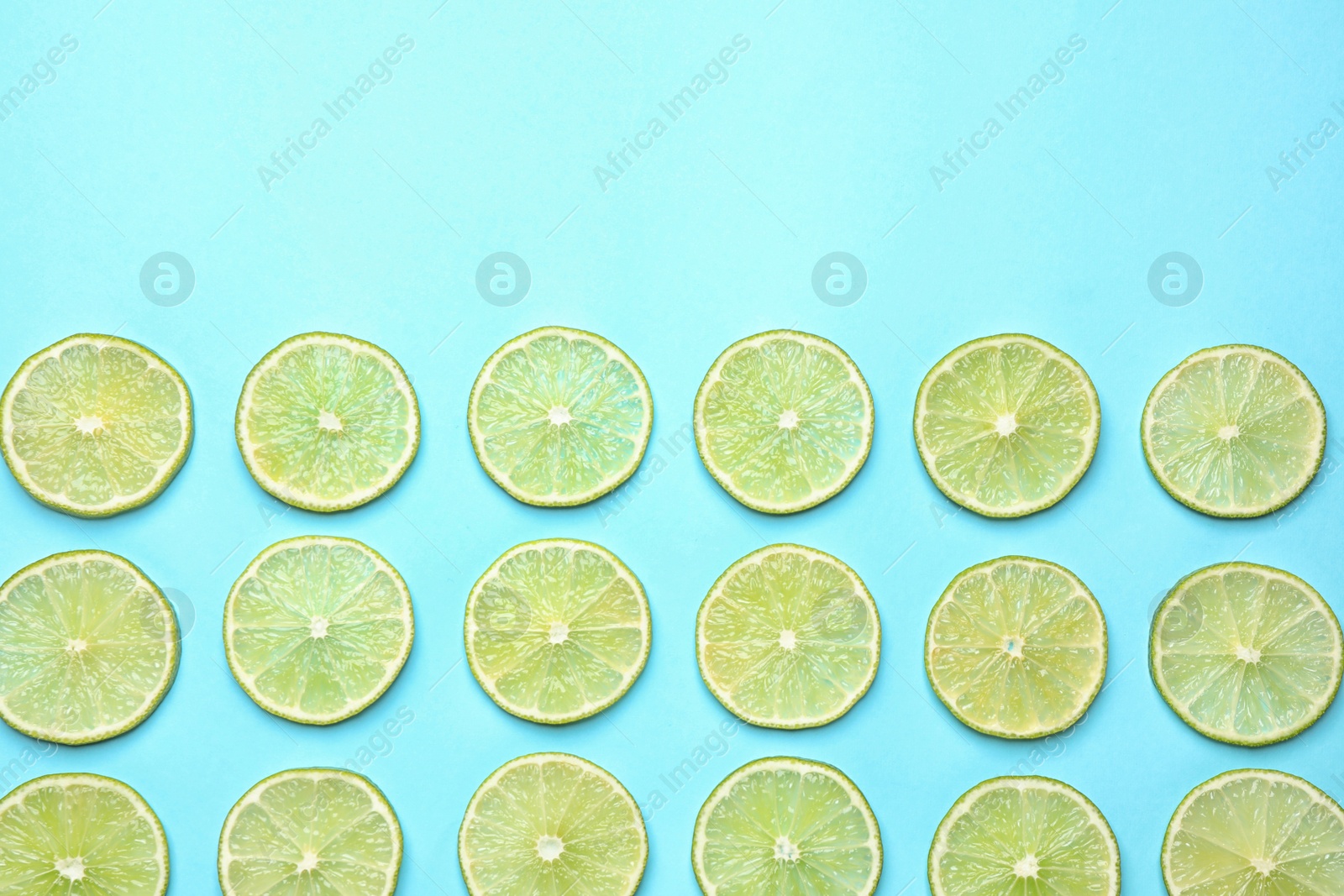 Photo of Fresh juicy lime slices on light blue background, flat lay. Space for text