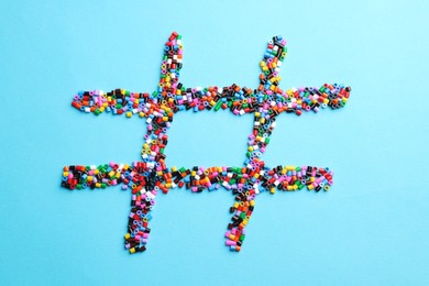 Hashtag symbol made of melty beads on light blue background, top view