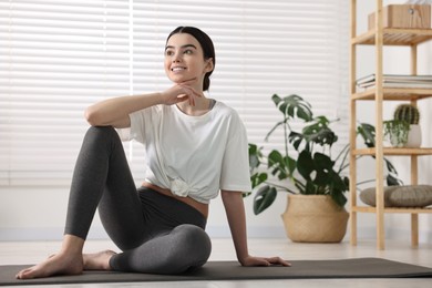 Photo of Beautiful girl sitting on yoga mat in studio