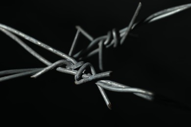 Photo of Shiny metal barbed wire on black background, closeup