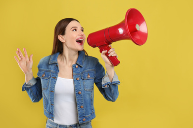 Young woman with megaphone on yellow background