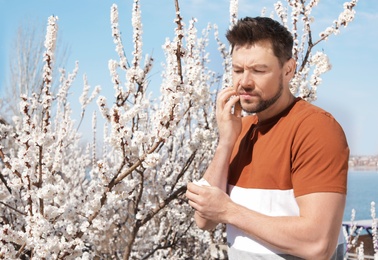 Photo of Man suffering from seasonal allergy outdoors, space for text