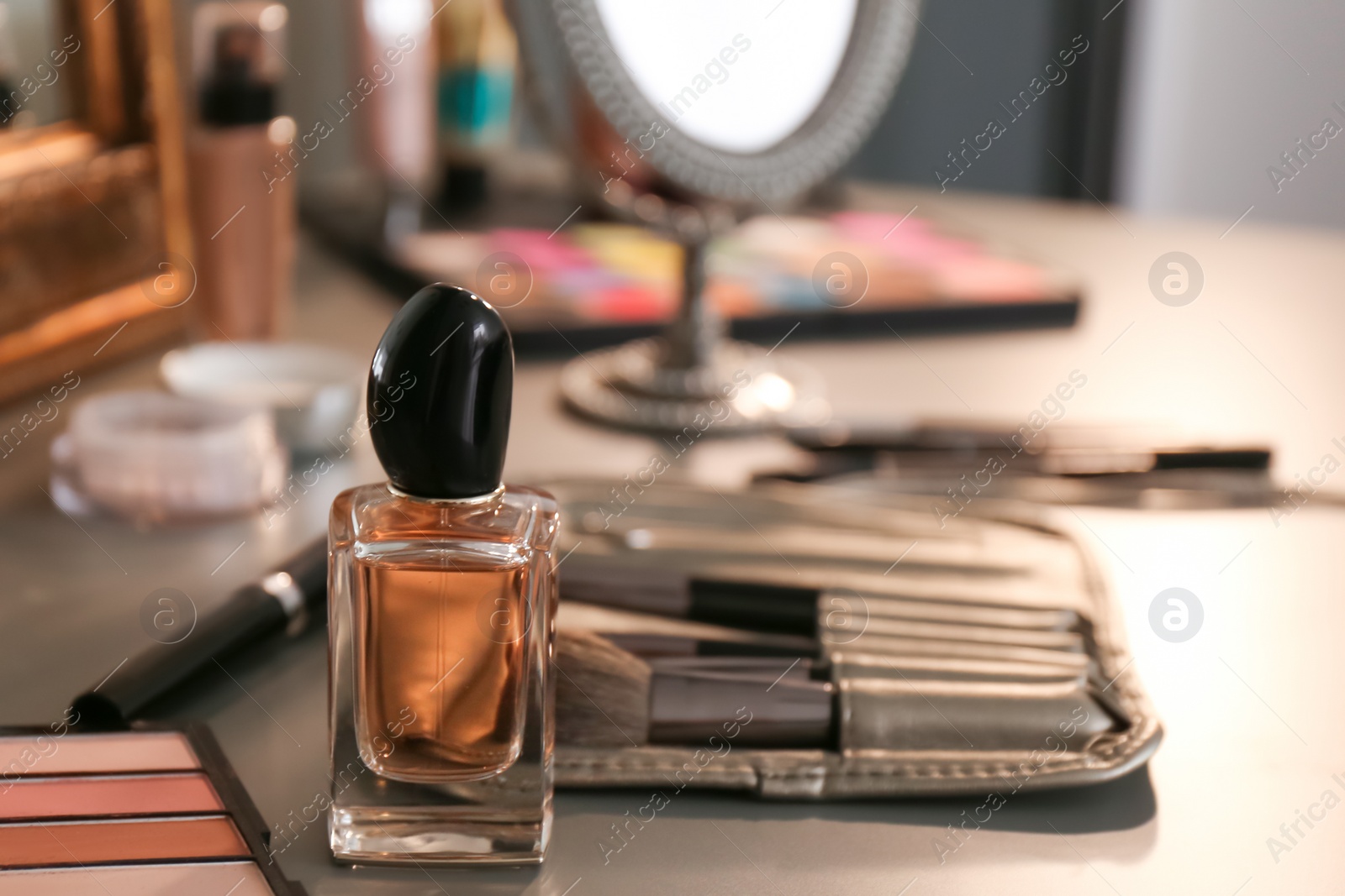 Photo of Bottle of perfume and makeup products on dressing table