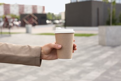 Coffee to go. Woman with paper cup of drink outdoors, closeup