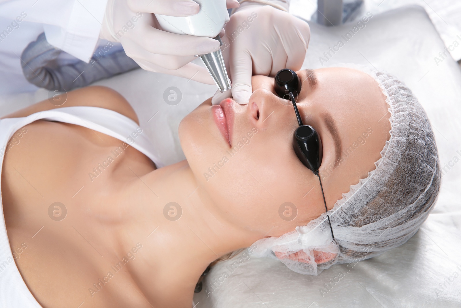 Photo of Young woman undergoing laser removal of permanent makeup in salon