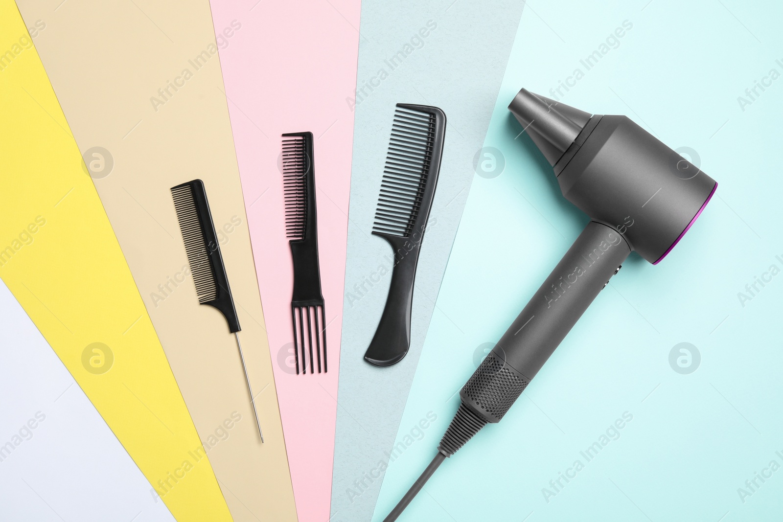 Photo of Hair dryer and different combs on color background, flat lay. Professional hairdresser tool