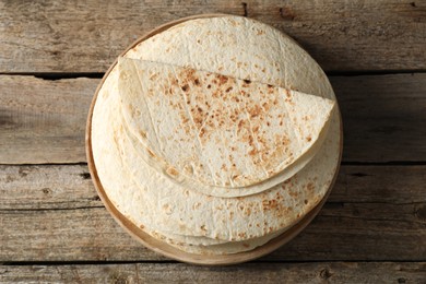 Photo of Stack of tasty homemade tortillas on wooden table, top view