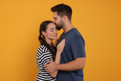 Photo of Man kissing his girlfriend on orange background