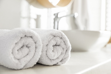 Photo of Clean rolled towels on countertop in bathroom