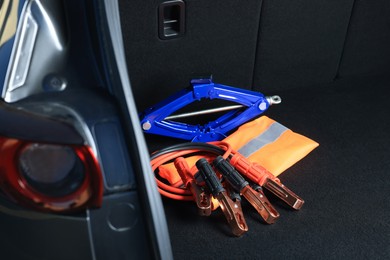 Photo of Scissor jack, life vest and battery jumper cables in trunk. Car safety equipment