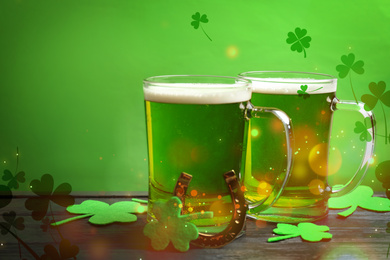 Green beer, horseshoe and clover leaves on wooden table. St. Patrick's Day celebration
