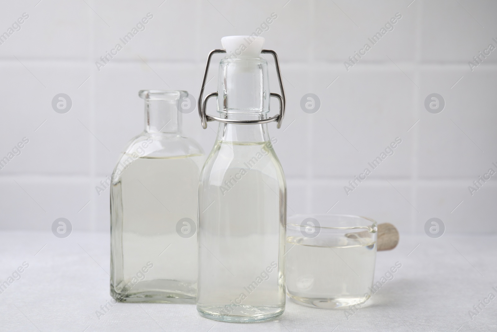 Photo of Vinegar in glass bottles and saucepan on light table