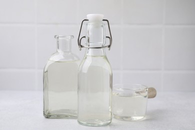 Vinegar in glass bottles and saucepan on light table