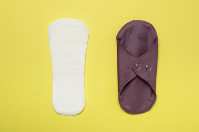 Photo of Pantyliner and reusable cloth menstrual pad on yellow background, flat lay
