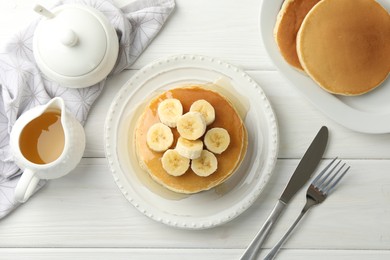 Photo of Delicious pancakes with bananas and honey served on white wooden table, flat lay