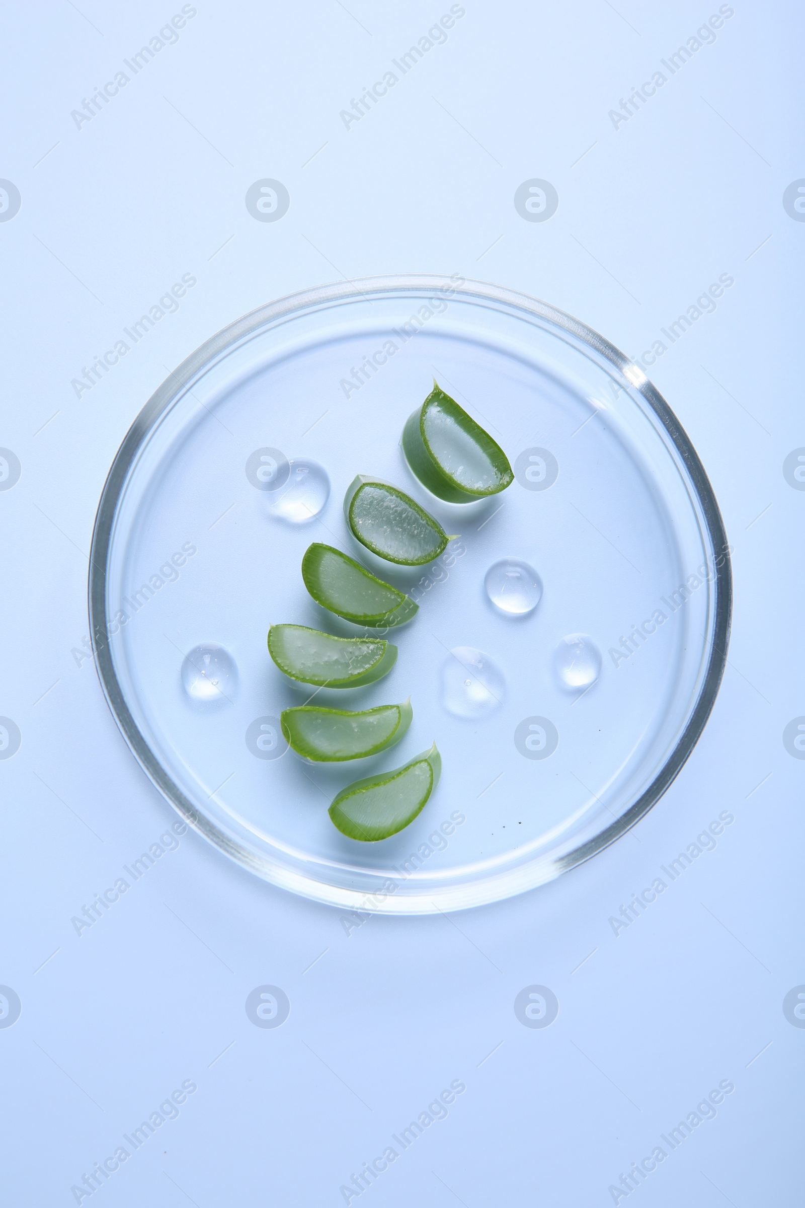 Photo of Cut aloe vera and drops of cosmetic gel on light blue background, top view