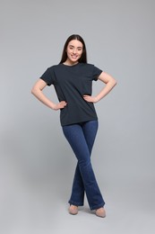 Young woman in stylish jeans on grey background