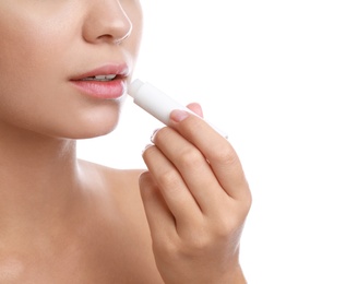 Young woman with cold sore applying lip balm against white background, closeup