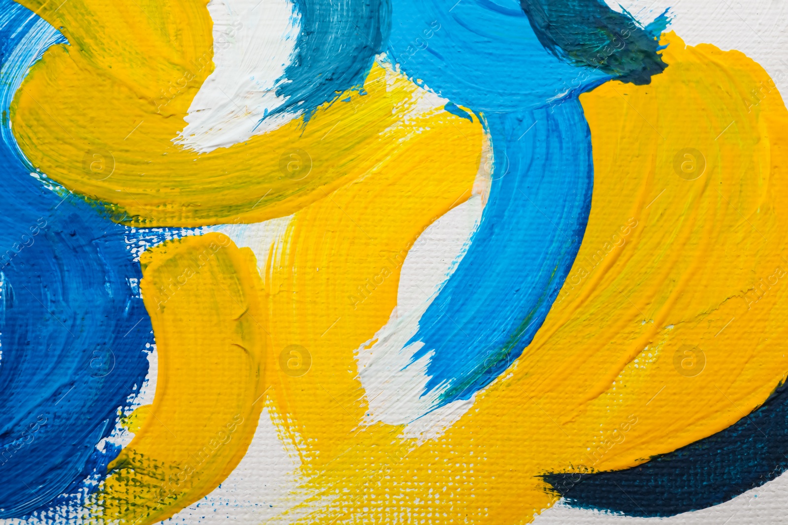 Photo of Beautiful strokes of blue and yellow oil paints on white canvas as background, closeup