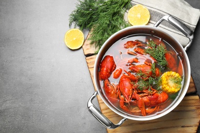 Photo of Fresh delicious crayfishes in pot on grey table, flat lay. Space for text