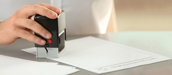 Image of Male notary stamping document at table, space for text. Banner design