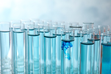 Photo of Many test tubes with light blue liquid, closeup