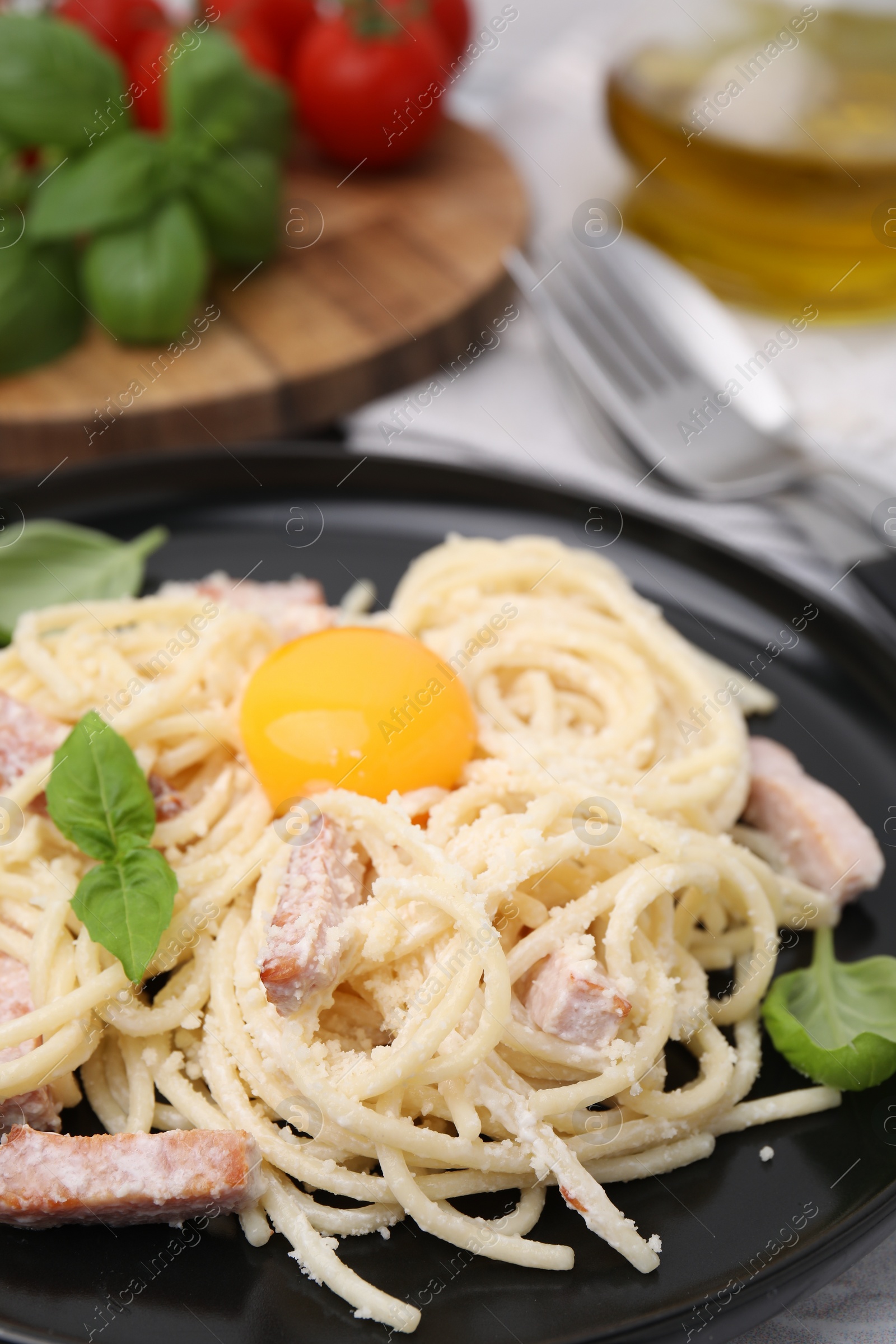 Photo of Tasty pasta Carbonara with basil leaves and egg yolk on plate, closeup