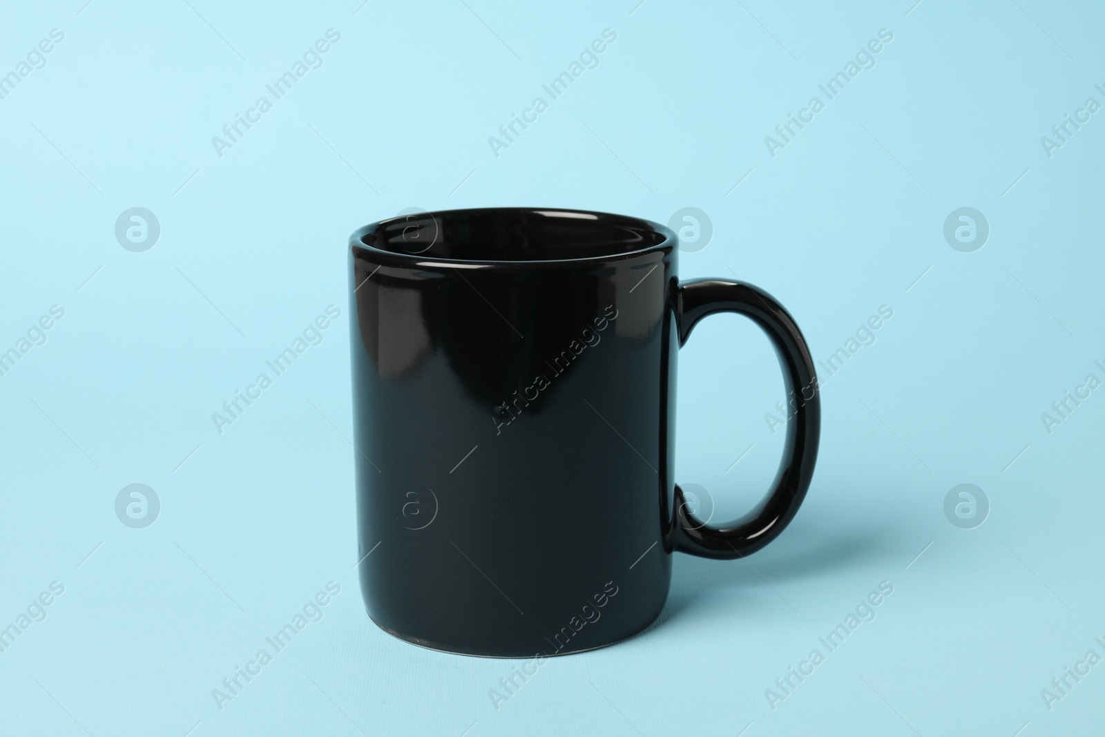 Photo of One black ceramic mug on light blue background