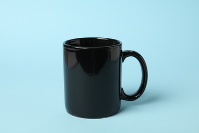 Photo of One black ceramic mug on light blue background