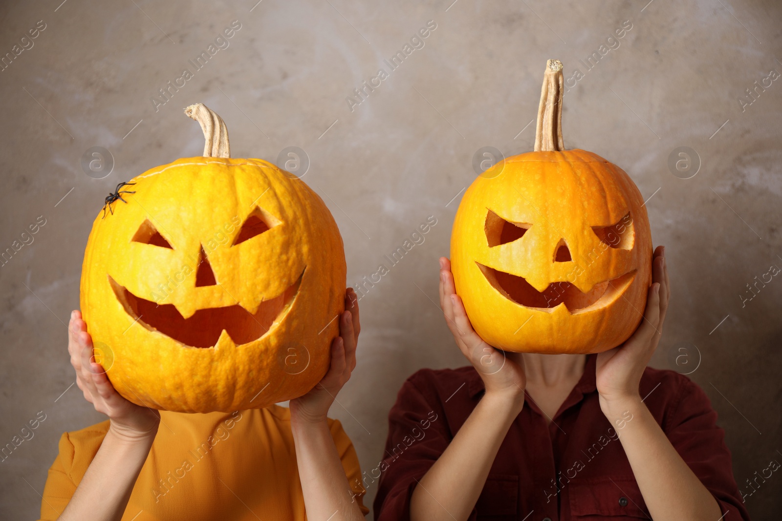 Photo of Women with pumpkin heads against beige background. Jack lantern - traditional Halloween decor
