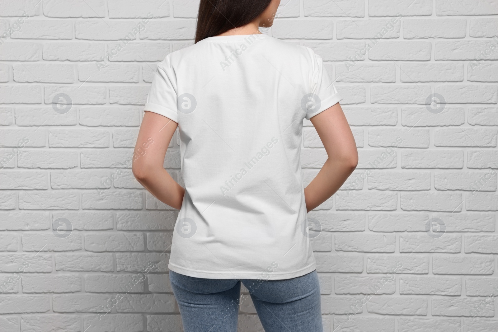 Photo of Woman wearing stylish T-shirt near white brick wall, closeup