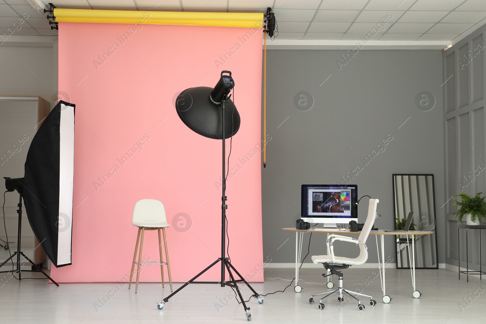 Photo of Pink photo background, workplace and professional lighting equipment in modern studio