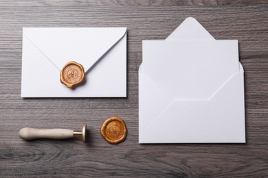 Photo of Envelopes with wax seal and stamp on wooden table, flat lay