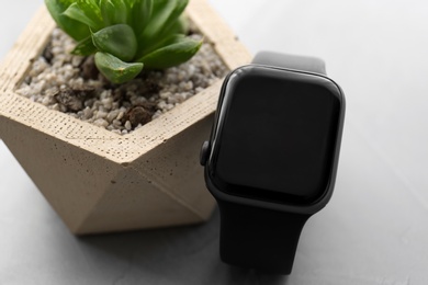 Photo of Stylish smart watch and plant on grey table, closeup