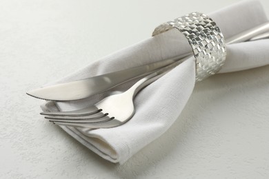 Photo of Stylish setting with cutlery and napkin on white textured table, closeup