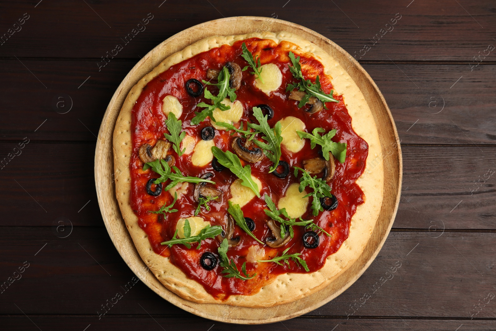 Photo of Pita pizza with cheese, olives, mushrooms and arugula on wooden table, top view