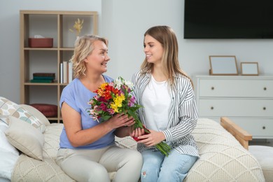 Young daughter congratulating her mom with flowers at home. Happy Mother's Day