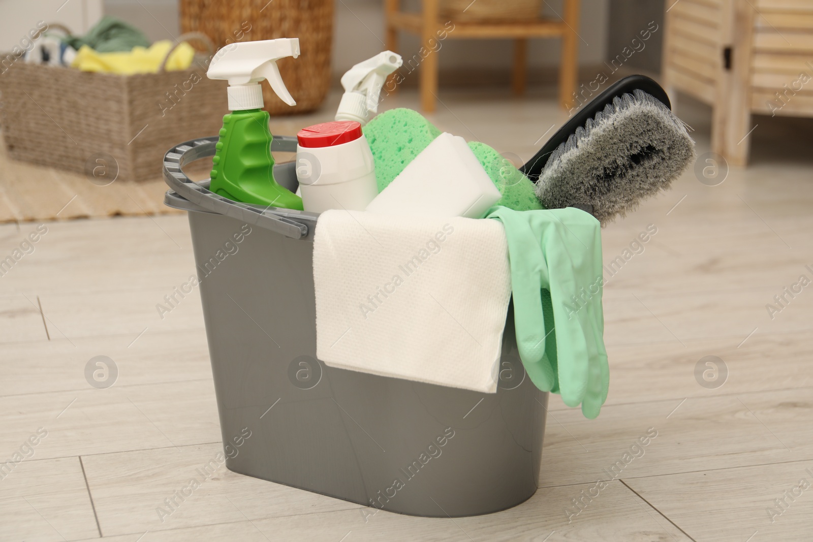 Photo of Different cleaning products in bucket on floor indoors