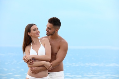 Photo of Young woman in bikini with her boyfriend on beach, space for text. Lovely couple