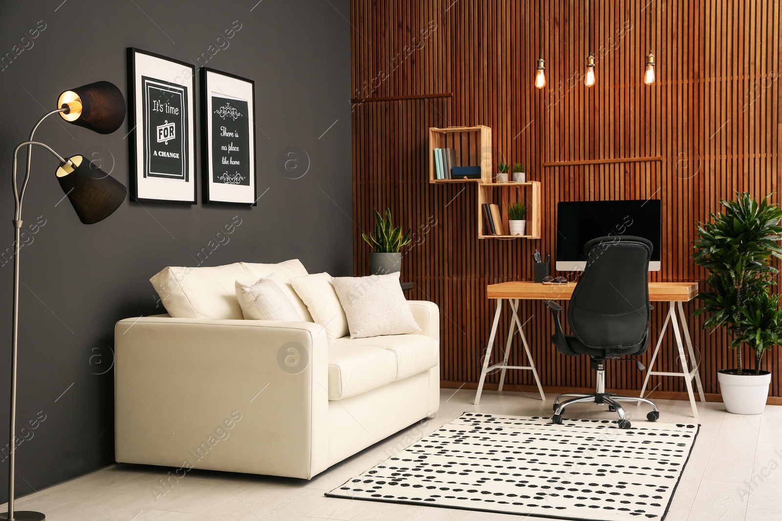 Photo of Comfortable workplace with computer near wooden wall in stylish room interior. Home office design