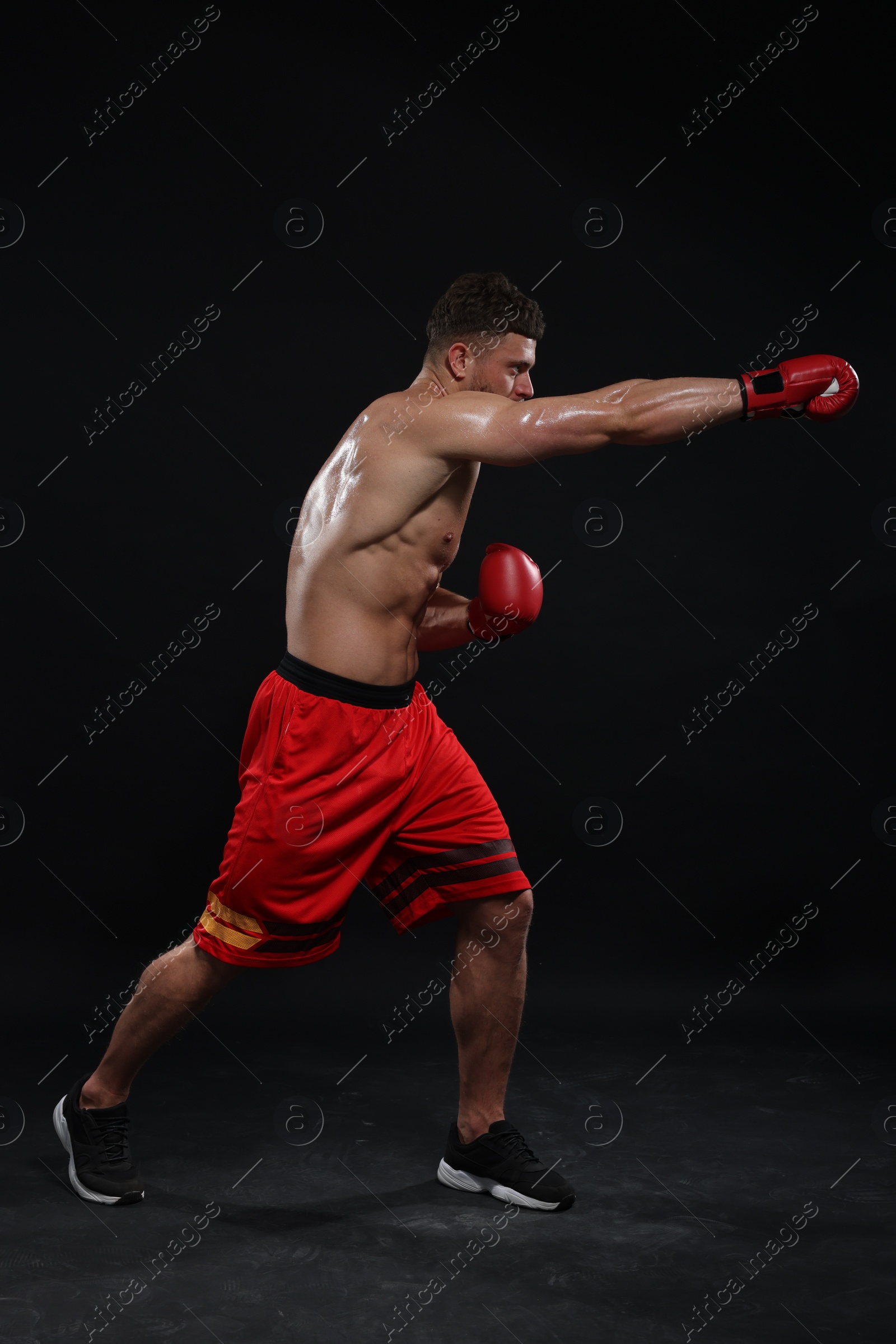 Photo of Man in boxing gloves fighting on black background