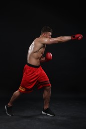 Photo of Man in boxing gloves fighting on black background