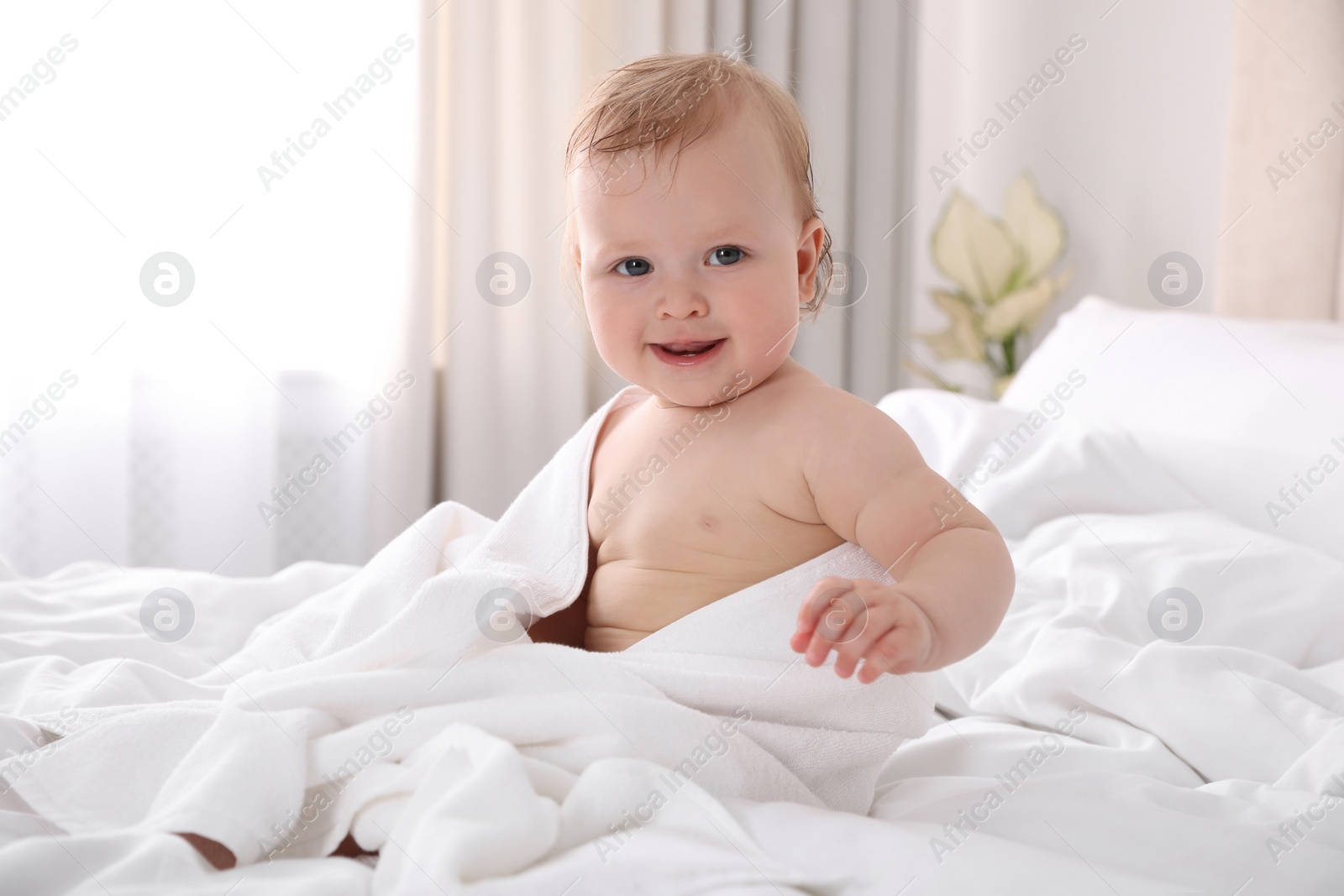 Photo of Cute little baby with soft towel on bed after bath